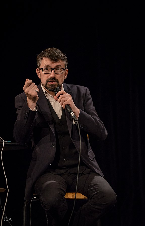 Thomas C. Durand assis sur une chaise lors du 79ième Live de la Tronche en Biais, à Nancy